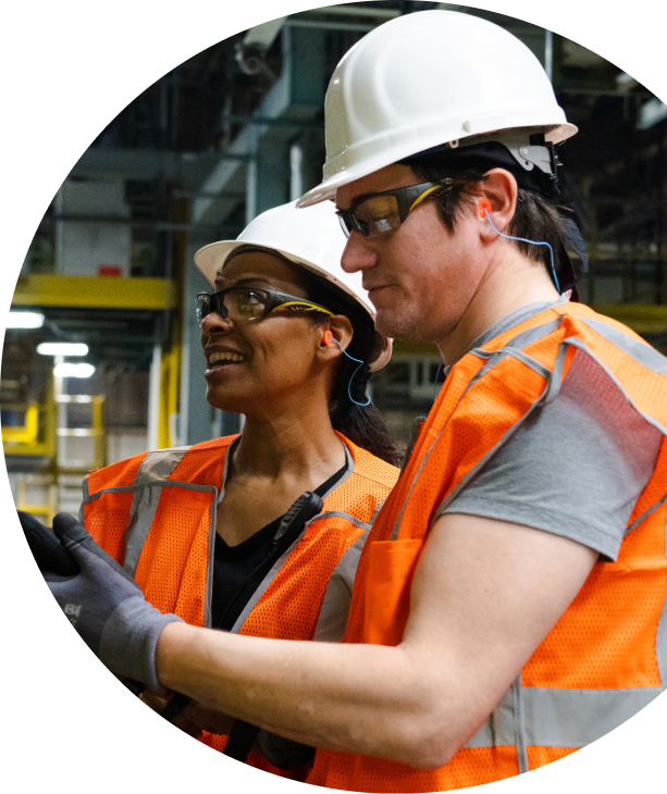 Two workers reviewing a tablet on the production floor