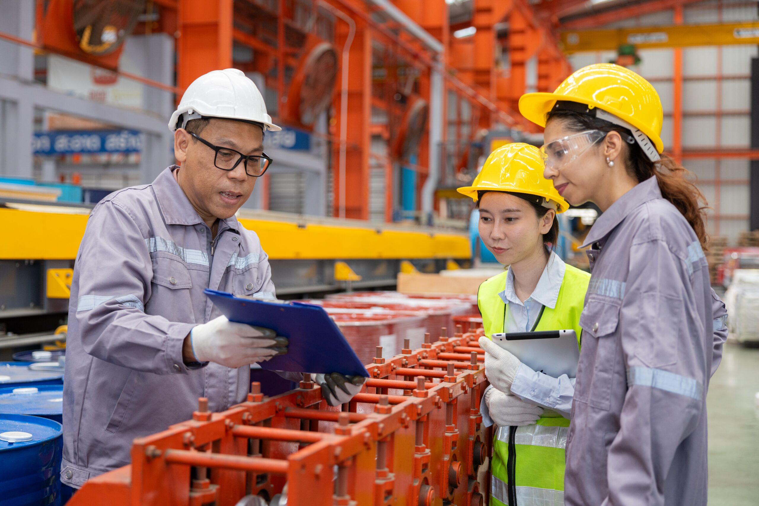 Supervisor walks two new hires through a procedure beside equipment on a manufacturing floor
